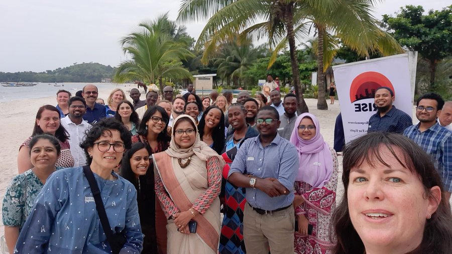 Group photograph of ARISE colleagues outside near the sea at the AGM